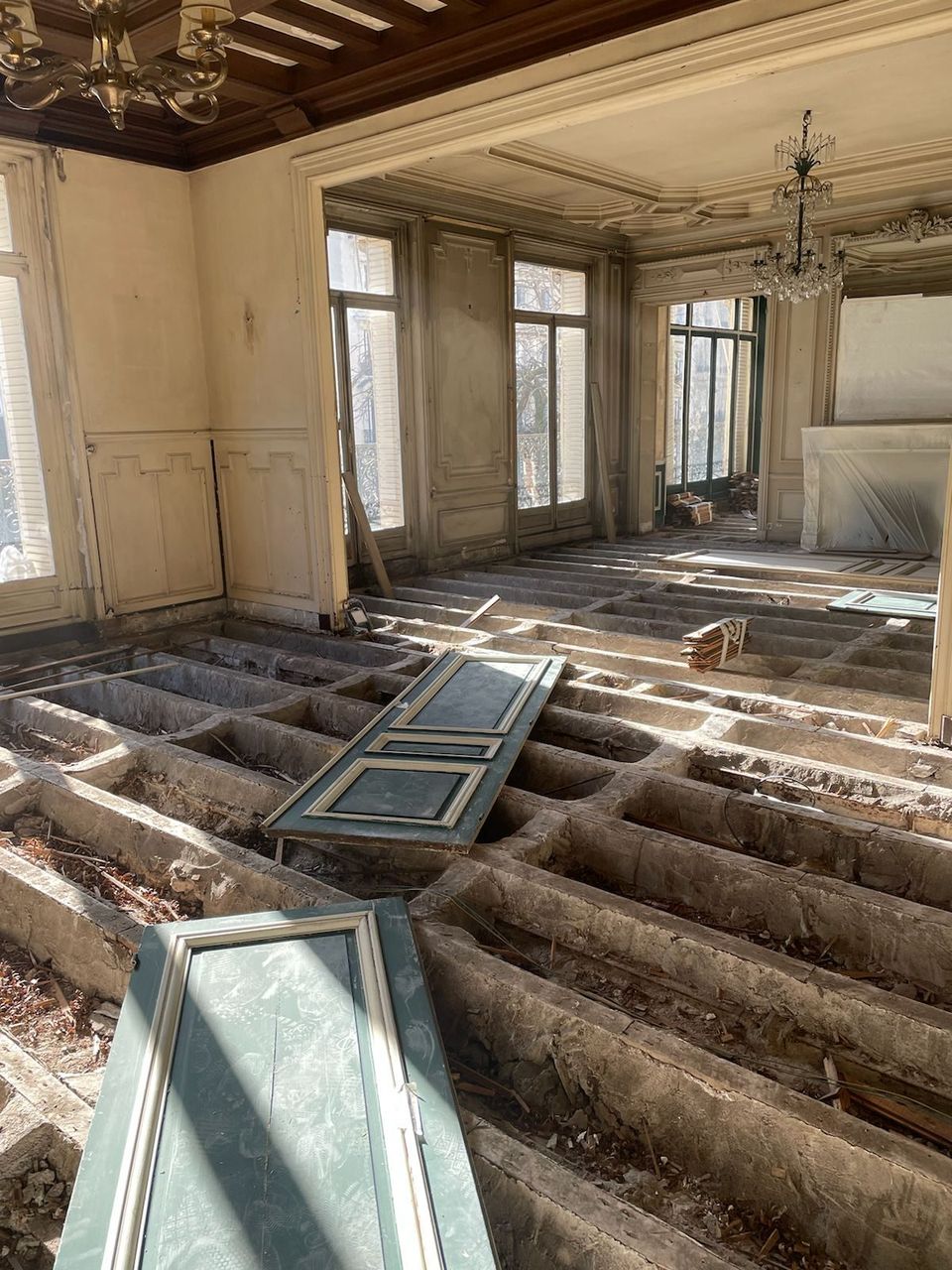 Salon haussmannien en chantier : parquet déposé, plancher mis à nu, boiseries et portes démontées